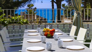 A dining table set for four with white plates, cups, and a fruit bowl. - Private swimming pool and jacuzzi in Cap Salou (Salou)
