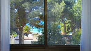 A window with a view of trees and a building in the background. - Private swimming pool and jacuzzi in Cap Salou (Salou)