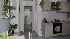 A modern kitchen with built-in appliances, wooden cabinets, and hanging plants. - Detached apartment (Salerno)