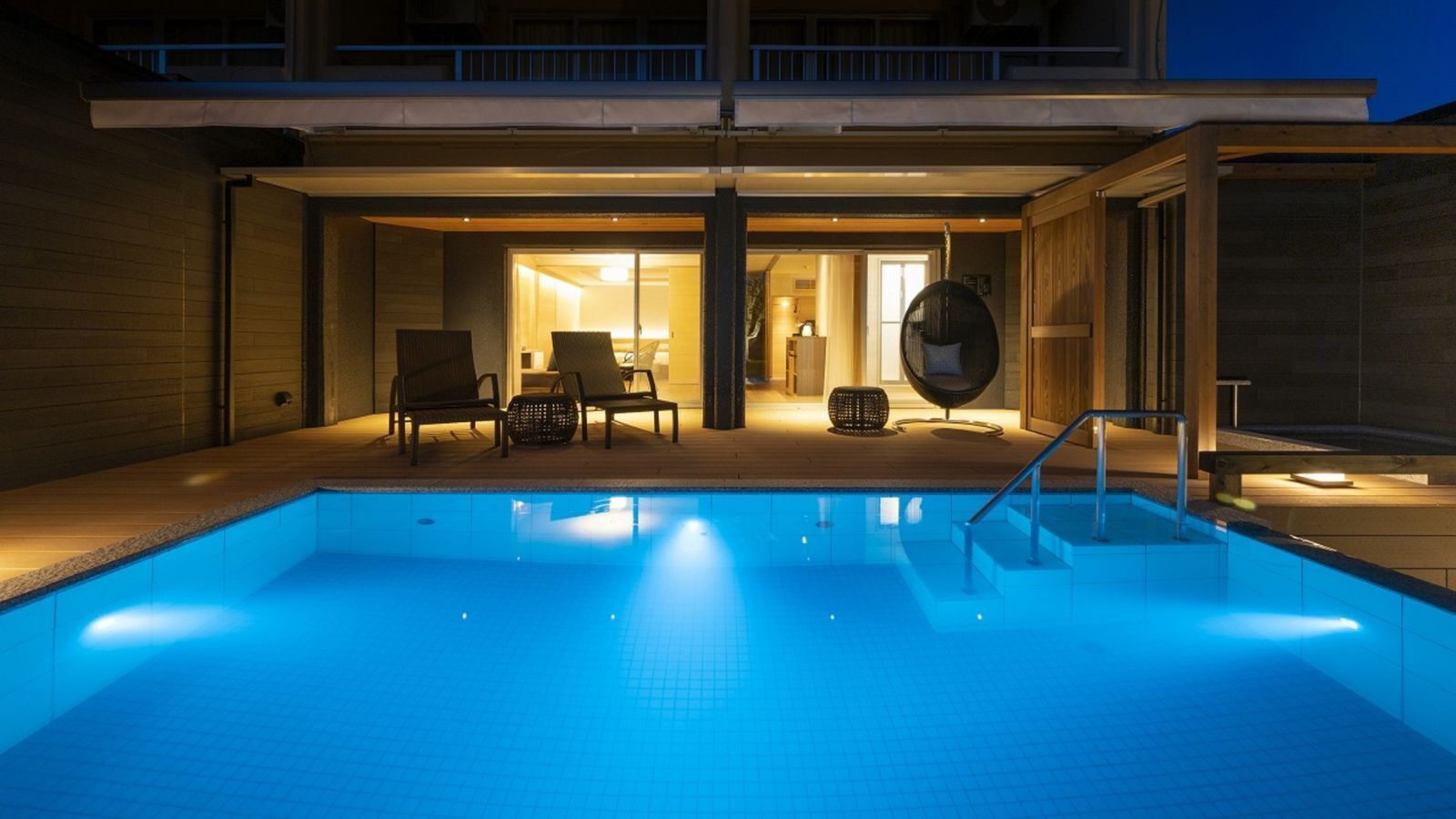 Una piscina con una zona de estar hundida, un porche cubierto y vistas al espacio interior.