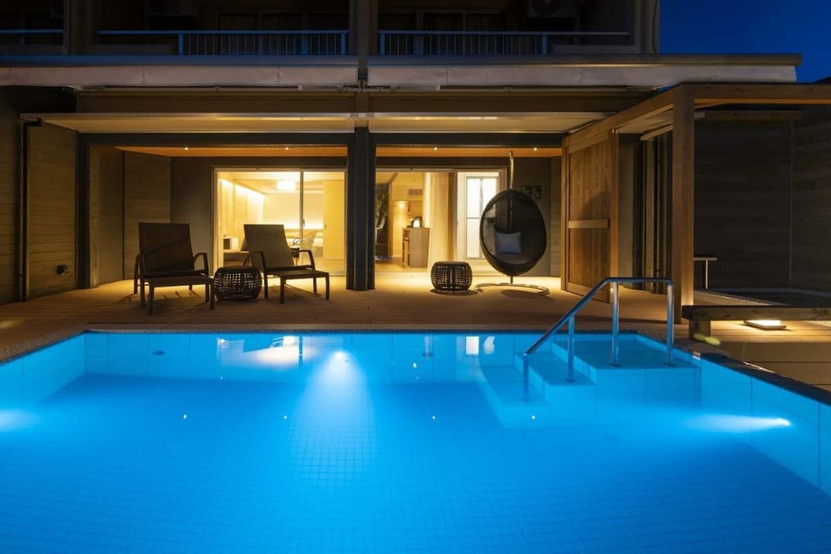 Una piscina con una zona de estar hundida, un porche cubierto y vistas al espacio interior.