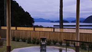 Een hottub met een houten omheining en uitzicht op een waterpartij en bergen.