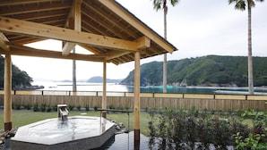 Een hottub onder een houten pergola, met uitzicht op een meer en bergen.