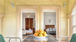 Una habitación con una mesa de comedor en el centro, una cama con cabecera de madera y una lámpara fijada a la pared.