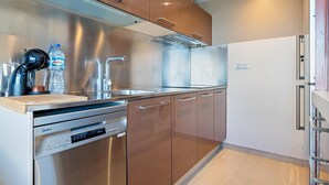 A modern kitchen with stainless steel appliances, wooden cabinets, and a built-in dishwasher.