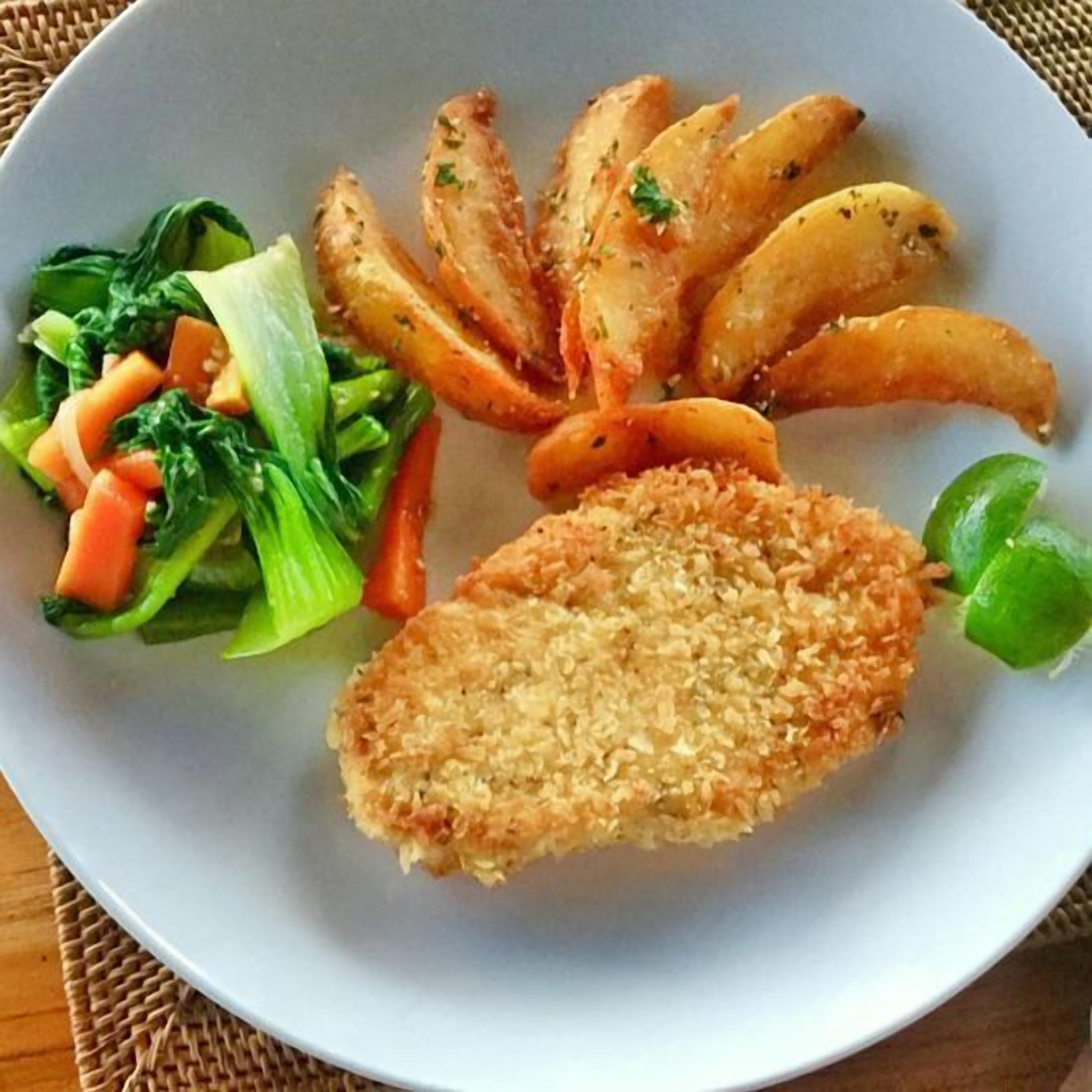 A plate with a breaded cutlet, roasted potatoes, and a side salad.