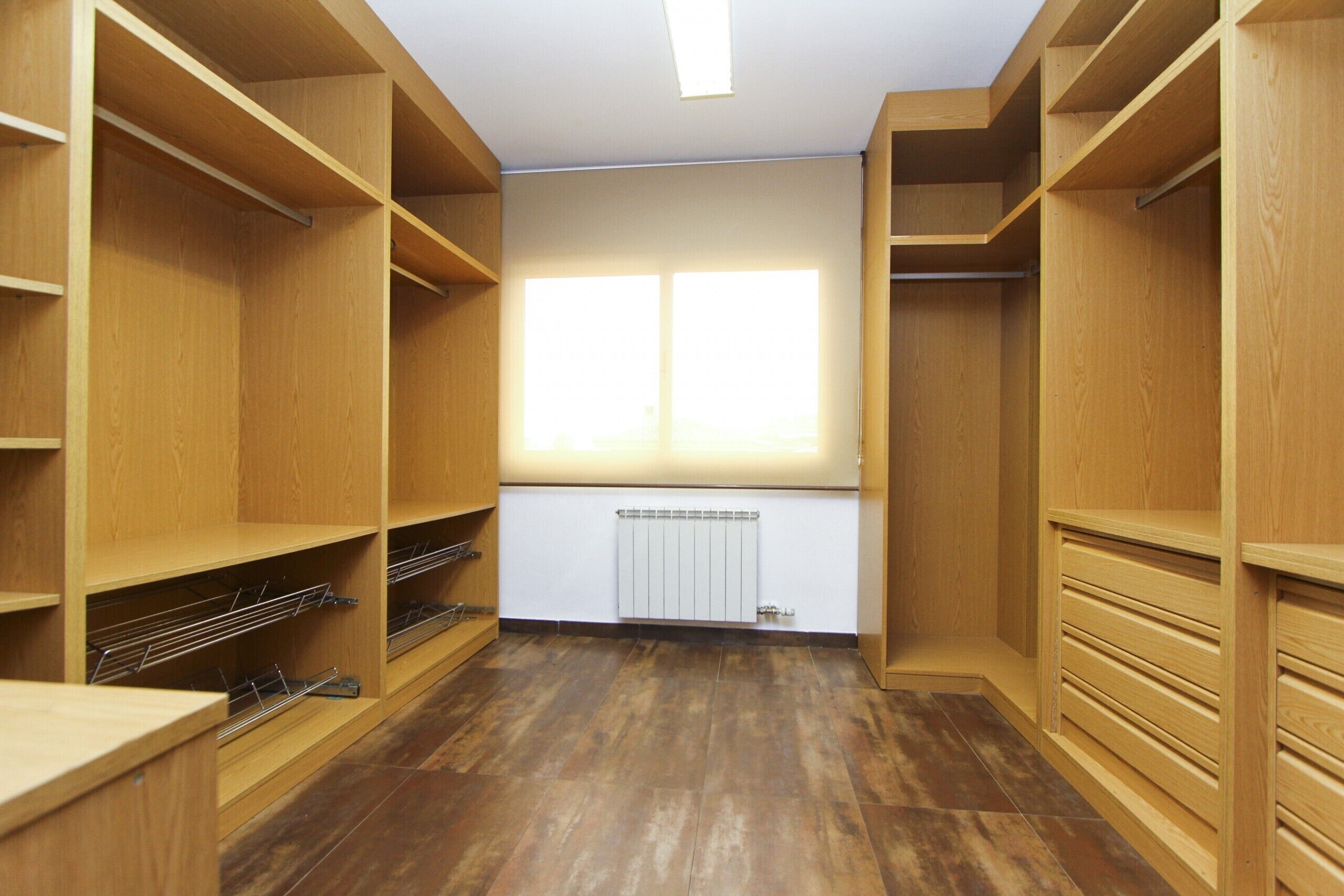 A walk-in closet with wooden shelving and a radiator.