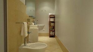 Une salle de bain avec un lavabo, des toilettes et une étagère avec des serviettes.