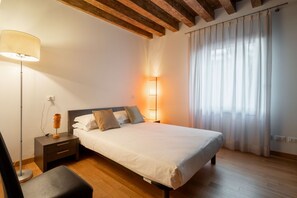 A bedroom with a bed, bedside tables, a lamp, and a window with curtains.