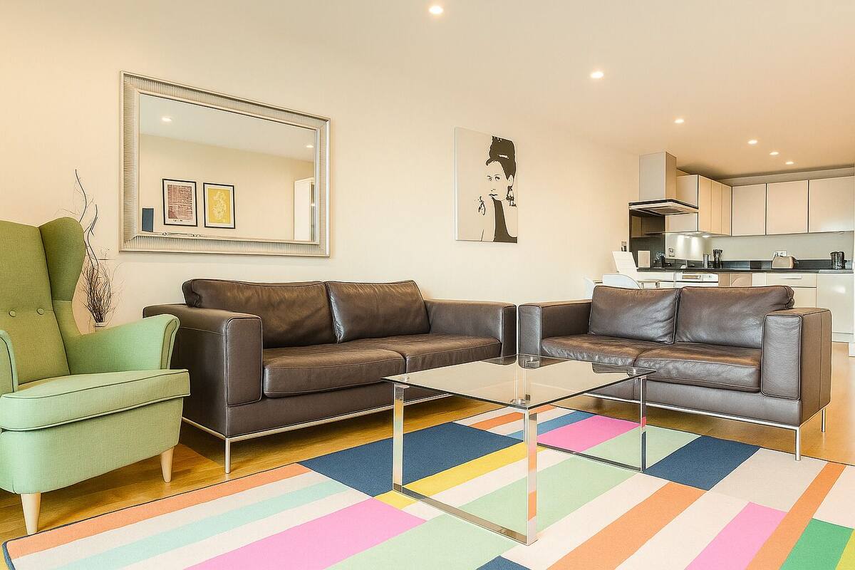 A modern living room with a brown leather sofa, a green armchair, and a glass coffee table.