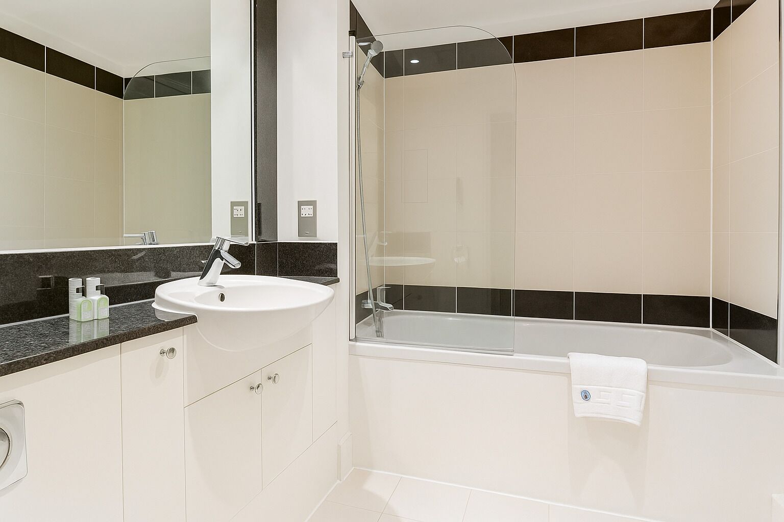 Une salle de bain moderne avec un lavabo blanc, un miroir, une douche et une baignoire.