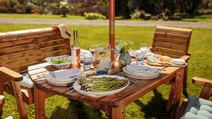 A wooden picnic table set outdoors with plates of food, glasses, and a bottle of wine. - 4* House / Beautiful Sea Views / Woodland Walks / Dog Friendly (Stranraer)