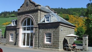 A stone building with a clock, arched windows, and a small outdoor seating area. - Stay somewhere unusual , Peaceful central location, sleeps 4, Pets Welcome. (Perth)