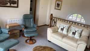 A living room with a blue leather chair, a wooden coffee table, a beige sofa with deer pillows, a framed landscape painting, and a chandelier. - Stay somewhere unusual , Peaceful central location, sleeps 4, Pets Welcome. (Perth)