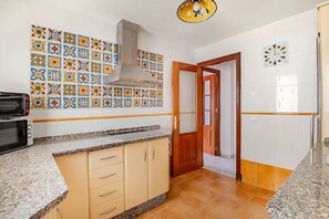 Una cocina con microondas, estufa y pileta. Hay una puerta que da a otra habitación.