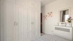 Et soveværelse med en stor garderobe, et sminkebord med spejl og et sengetæppe med et mønster.