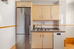 Eine Küche mit einem Edelstahl-Kühlschrank, beigen Schränken, einer Spüle und einem Geschirrspüler.