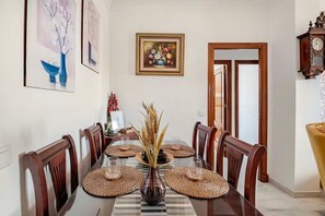 Un comedor con una mesa larga, sillas y un jarrón con plantas secas.