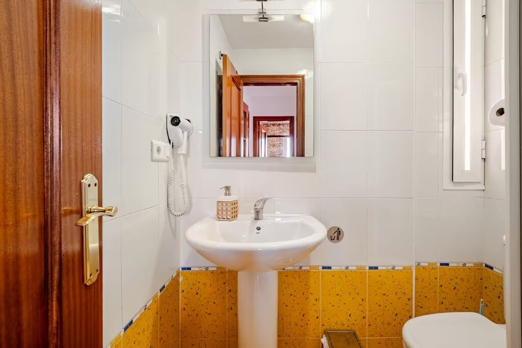 Un baño con lavamanos blanco, un espejo y un inodoro.