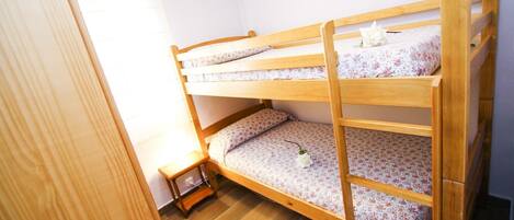 Een stapelbed met bloemenbeddengoed in een kamer met houten vloeren en een klein nachtkastje.