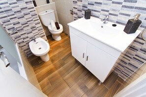 A modern bathroom with a toilet, bidet, and sink.