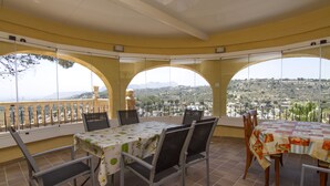 A dining area with a table set for four, large windows offering a view of a mountainous landscape, and a balcony with a railing. - Villa Aline between Moraira and Calpe, private pool, WIFI, air conditioning, (Benissa)