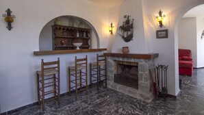 A stone fireplace with a wooden mantel, a stone bench, and a wooden bar with stools. - Villa Aline between Moraira and Calpe, private pool, WIFI, air conditioning, (Benissa)