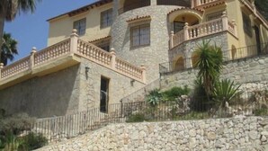 A multi-story building with stone walls, balconies with railings, and a stone staircase leading to the entrance. - Villa Aline between Moraira and Calpe, private pool, WIFI, air conditioning, (Benissa)