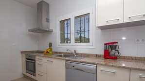 A modern kitchen with white cabinets, a stainless steel range hood, a dishwasher, a double sink, and a red coffee maker. - Villa Aline between Moraira and Calpe, private pool, WIFI, air conditioning, (Benissa)