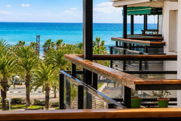 A balcony with a view of the ocean and palm trees.