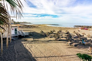 Ein Strand mit Sonnenschirmen, Liegestühlen und einem Rettungsschwimmerstand.
