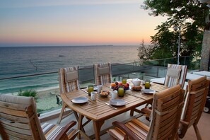 A wooden table set for breakfast with a view of the sea at sunset. - Infinity Beach House (Kefalonia)