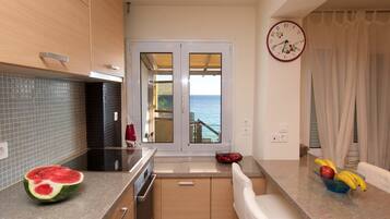 A kitchen with a view to the sea, a clock, and a fruit bowl.
