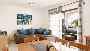 Ein Wohnzimmer mit einer Couch, einem Esstisch und einem Gemälde an der Wand.
