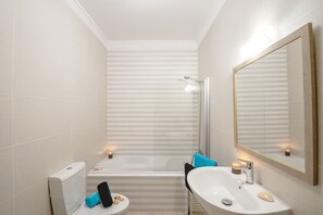 Un baño con bañera, lavabo, espejo y perchero para toallas.