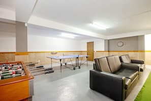 Um quarto com mesa de pebolim, mesa de tênis de mesa e um sofá.