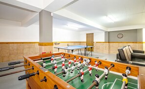 Ein Raum mit Kicker, Tischtennisplatte und Dartscheibe.