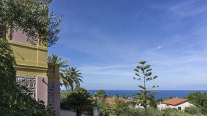 Un bâtiment à la façade jaune, doté d’une terrasse pavée et offrant une vue sur la mer.