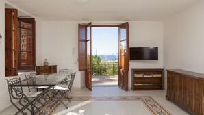 Un coin repas avec une table et des chaises en verre, un meuble en bois et un téléviseur fixé au mur.