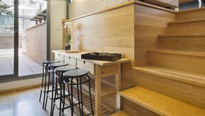 Una cocina moderna con encimeras de madera, estufa empotrada y una zona de comedor con taburetes.