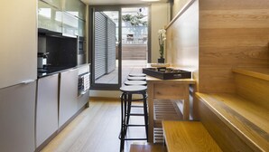 Una cocina compacta con electrodomésticos modernos, una zona de comedor con taburetes y un banco de madera.