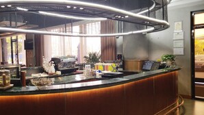 Eine moderne Hotelhalle mit einer gebogenen Rezeption, einer Kaffeemaschine und einem großen Fenster mit Vorhängen.