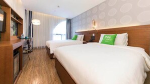 Ein Hotelzimmer mit zwei Betten, einem Schreibtisch und einem Fernseher.