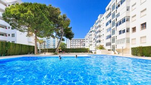 Una piscina envoltada d'edificis moderns, sota un cel blau i clar.