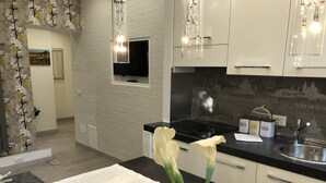 Eine moderne Küche mit schwarzem Arbeitsplatz, Spüle aus Edelstahl und einer Glasvase mit Blumen.
