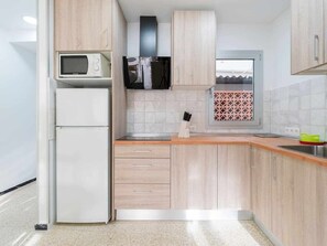 A modern kitchen with a microwave, refrigerator, and wooden cabinets. - Bldg.  Balandra Apt (Corralejo)