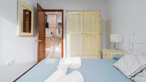 Quarto com cama, mesa de cabeceira, guarda-roupa e espelho.