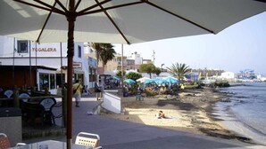 Um café à beira-mar com mesas ao ar livre e vista para o mar.