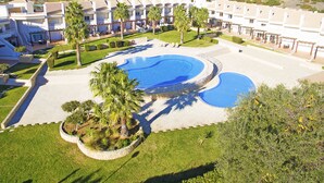A resort with multiple swimming pools, a well-maintained lawn, and a row of villas.