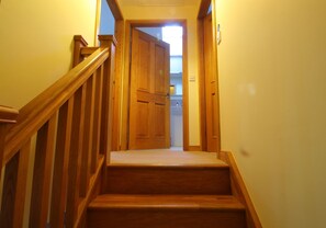A wooden staircase leading to a room with a door at the top.